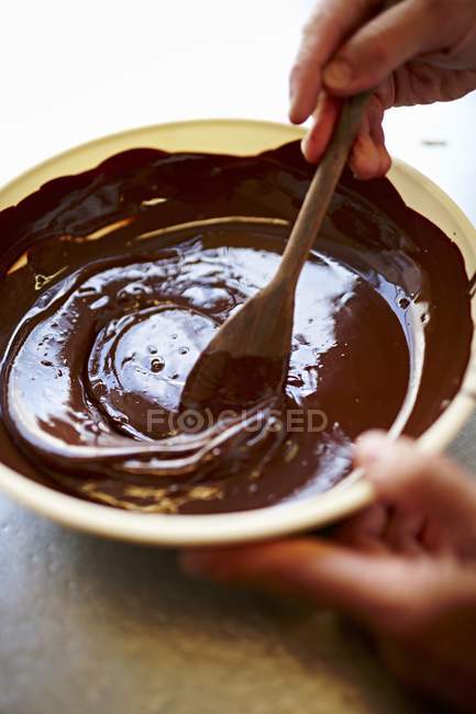 Manos revolviendo glaseado de chocolate - foto de stock
