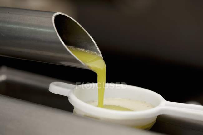 Olivenöl fließt von einem Kuchen in ein Sieb — Stockfoto