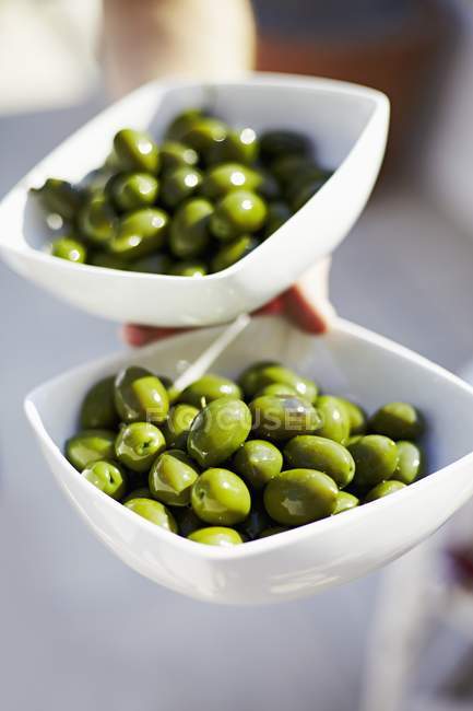 Рука держит чаши с зелеными оливками — стоковое фото