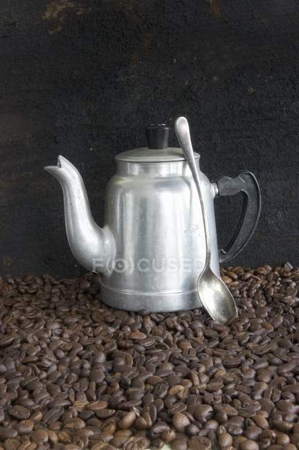 Jarro de café e colher em grãos de café — Fotografia de Stock