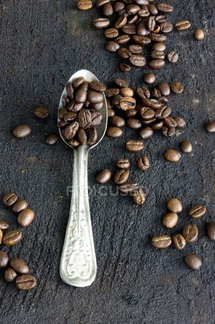 Chicchi di caffè su cucchiaio di alluminio — Foto stock