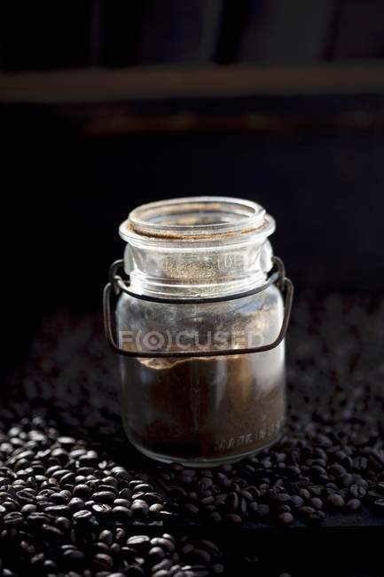 Vue rapprochée d'un pot de poudre de café sur les grains de café — Photo de stock