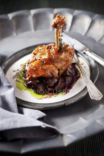 Duck confit on bed of potato slices — Stock Photo