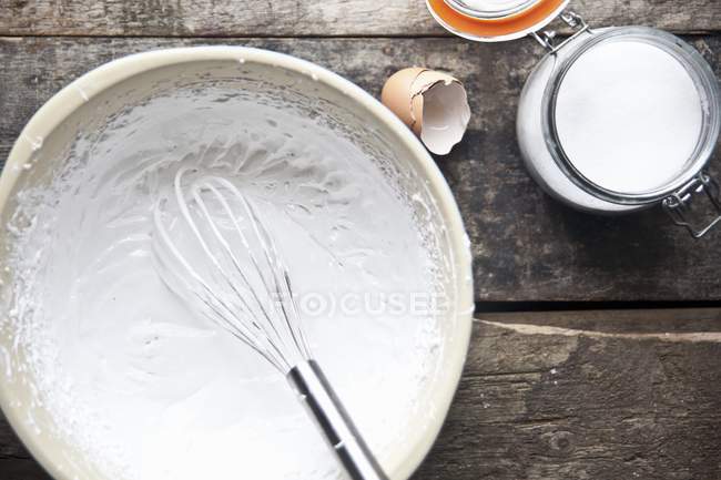 Vista superior de claras de ovo com açúcar e um batedor em uma tigela — Fotografia de Stock