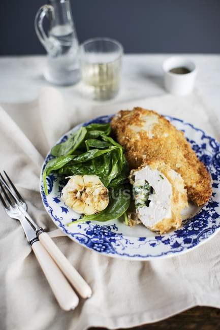 Hühnerkiev mit Spinat auf weißem und blauem Teller über Tuch — Stockfoto