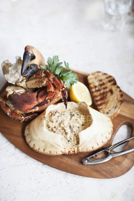 Nahaufnahme eines gefüllten Krabbenpanzers mit Toastbrot, Zitronenhälfte und Kräutern — Stockfoto