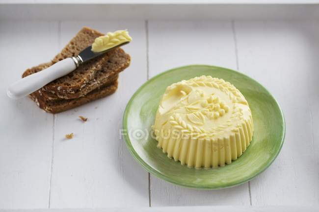 Vista elevada da manteiga em forma de modelo com fatias de pão e faca — Fotografia de Stock