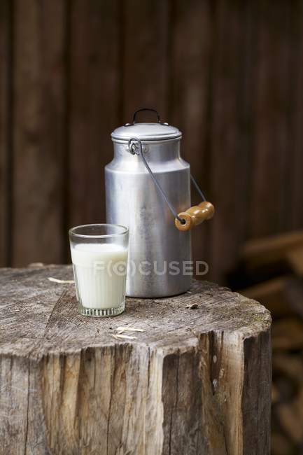 Glass of milk with a milk churn — Stock Photo