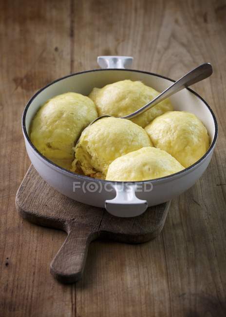 Closeup view of Dampfnudeln sweet yeast dumplings with spoon in bowl — Stock Photo
