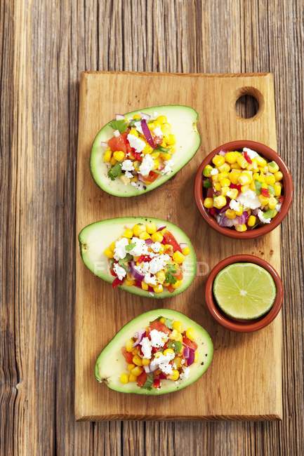 Stuffed avocados with corn salsa on wooden desk over table — Stock Photo