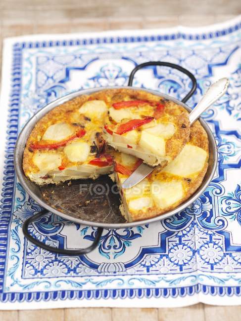 Tortilla de pomme de terre avec poivron rouge sur serviette blanche et bleue colorée — Photo de stock