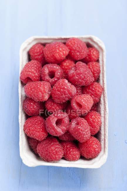 Raspberries in paper punnet — Stock Photo