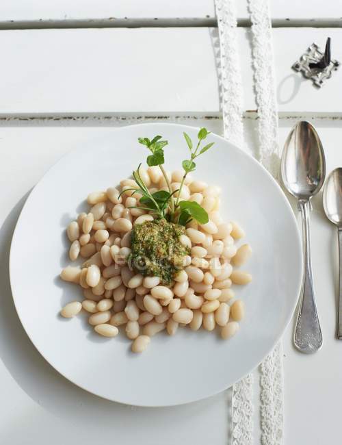 Салат из белых бобов с соусом из трав на белой тарелке — стоковое фото