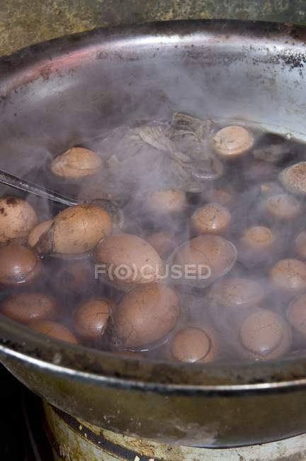 Vista elevada de huevos hirviendo en té - foto de stock