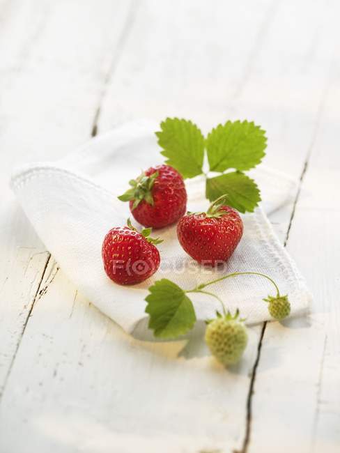 Strawberries with leaves on cloth — Stock Photo