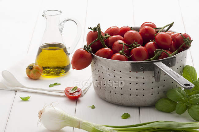 Tomatoes in colander and basil — Stock Photo