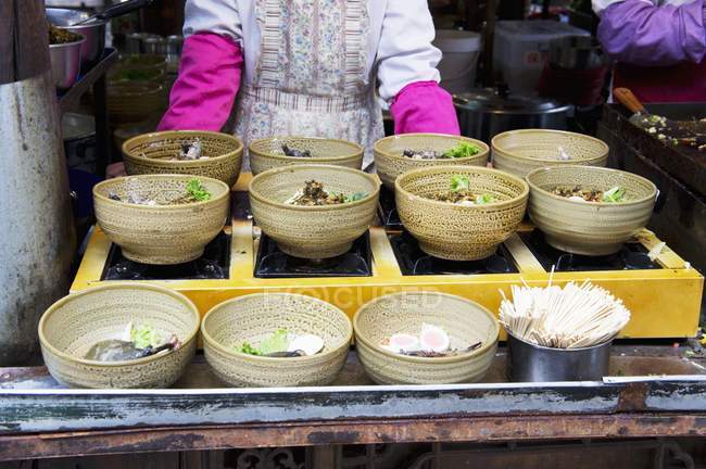Bols de soupe dans un restaurant asiatique avec un cuisinier sur fond — Photo de stock