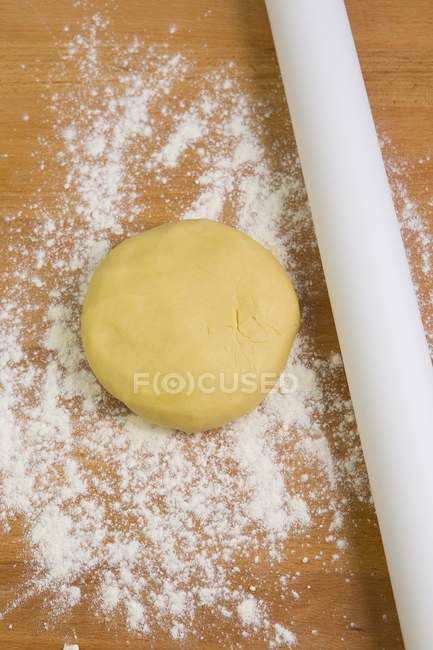 Elevated view of shortcrust pastry and a rolling pin on a floured surface — Stock Photo