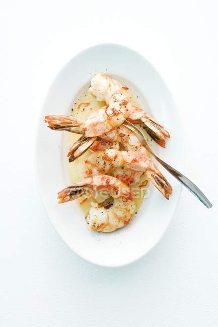 Top view of scampi with sauce and fork on white plate — Stock Photo