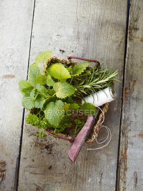 Hierbas frescas con cordel de cocina y un cuchillo en una canasta - foto de stock