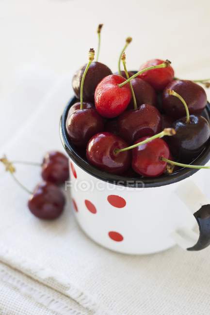 Cherries in enamel mug — Stock Photo