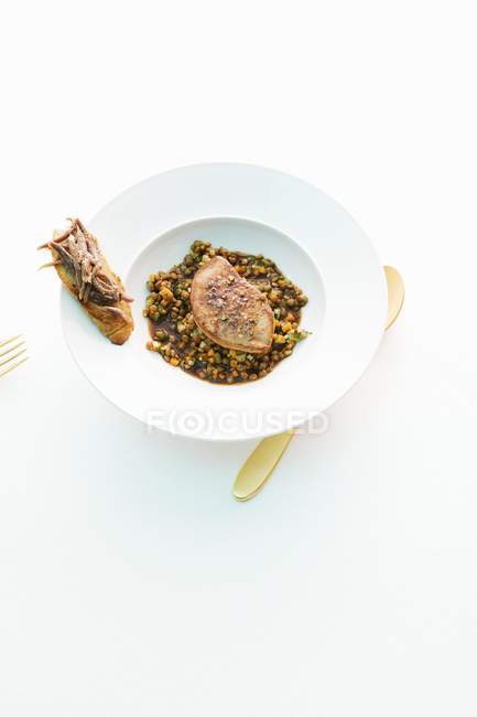 Elevated view of duck liver on lentils in white bowl — Stock Photo