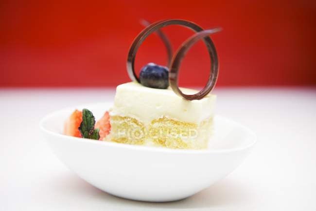 Vue rapprochée de l'éponge vanille ornée d'une spirale de chocolat, myrtille, fraise et menthe — Photo de stock