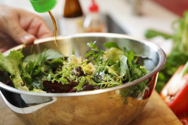 Uma salada de jardim fresca sendo regada com molho de soja — Fotografia de Stock