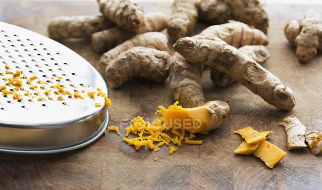 Fresh turmeric roots with grater — Stock Photo