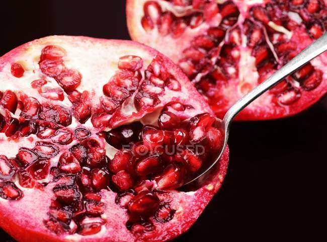 Halved pomegranate with spoon — Stock Photo