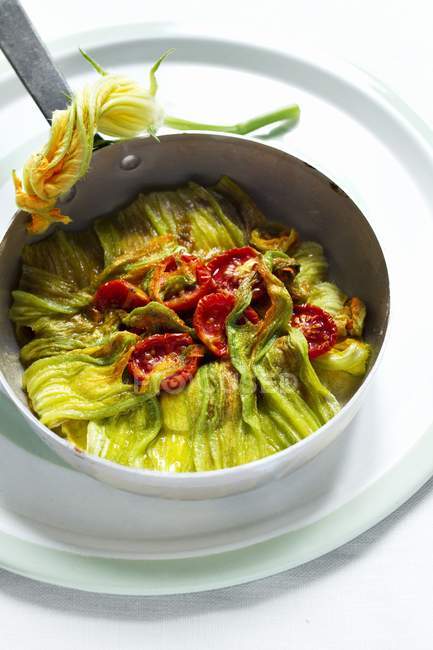 Courgette flower omelette in saucepan over white surface — Stock Photo