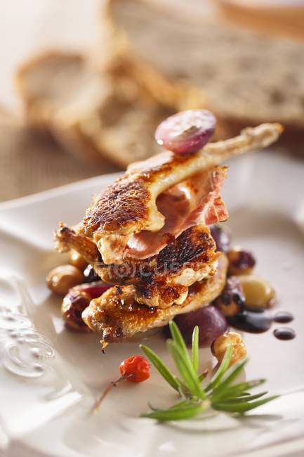 Closeup view of grilled quail with bacon, herb and sauce — Stock Photo