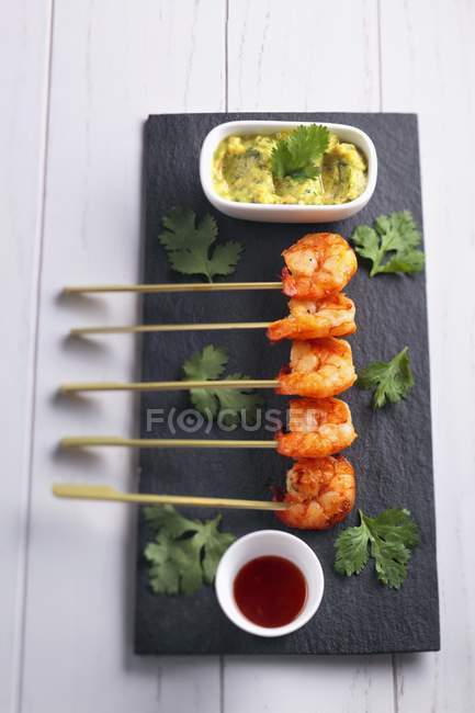 Prawn skewers with guacamole and coriander on black desk — Stock Photo