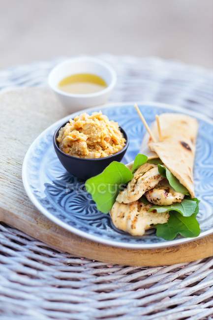 Un involucro di pollo con hummus sul piatto blu — Foto stock