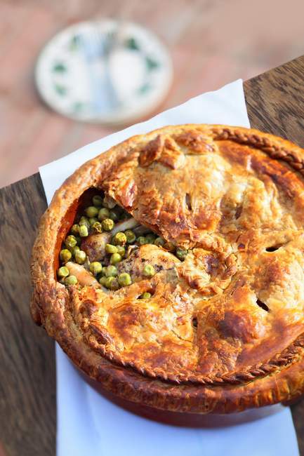 Chicken pie with peas over wooden surface — Stock Photo