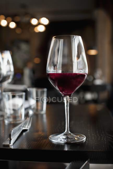 Copa de vino tinto en la mesa - foto de stock