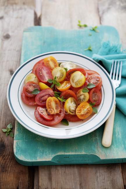 Erhöhter Blick auf Tomatensalat mit drei verschiedenen Tomatensorten, garniert mit Basilikum — Stockfoto