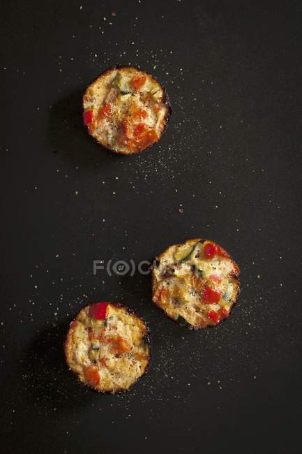 Mini quiches com tomate, ovo e courgette na superfície preta — Fotografia de Stock
