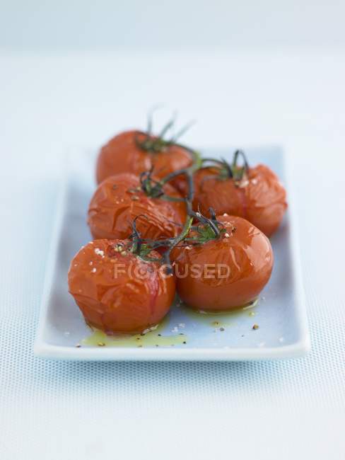 Roasted tomatoes with salt and olive oil  on white plate — Stock Photo