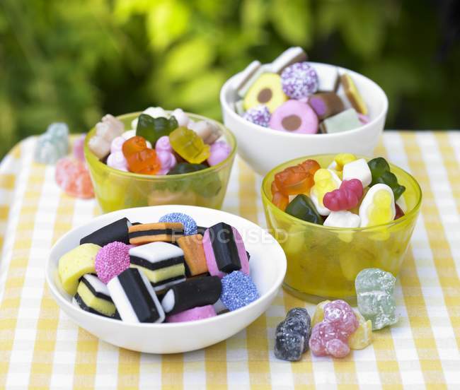 Four bowls of colorful sweets on outdoor table — Stock Photo