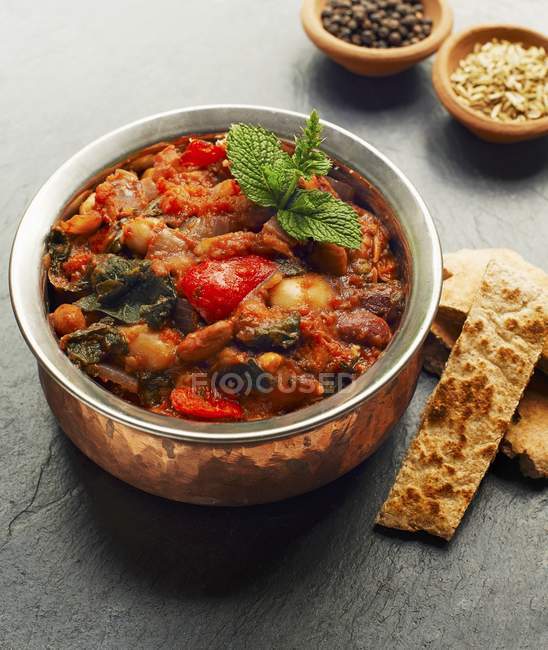 A casserole made with beans, peppers and spinach over wooden surface — Stock Photo