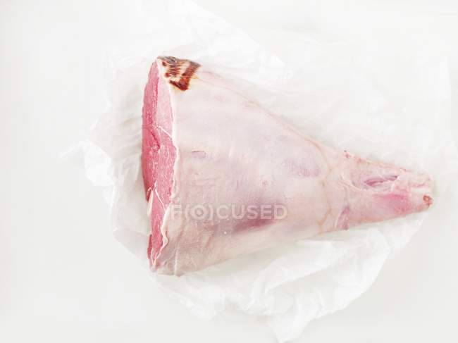 Raw leg of lamb on piece of paper — Stock Photo