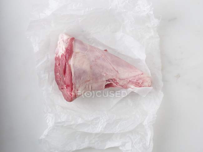 Perna crua de cordeiro sobre pedaço de papel — Fotografia de Stock