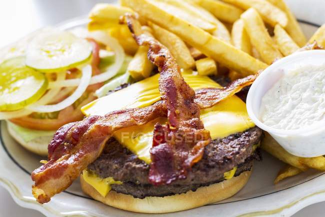 Cheeseburger with bacon and potato fries — Stock Photo