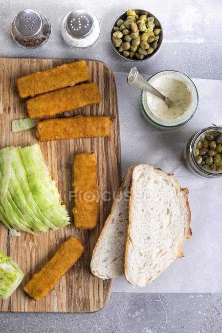 Um sanduíche de dedo de peixe com molho tártaro e alcaparras sendo feitas — Fotografia de Stock
