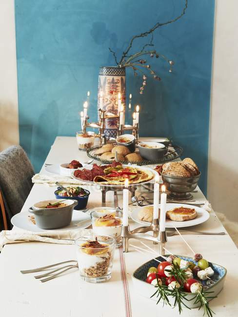 Накрытый стол с различными блюдами и горящими свечами — стоковое фото