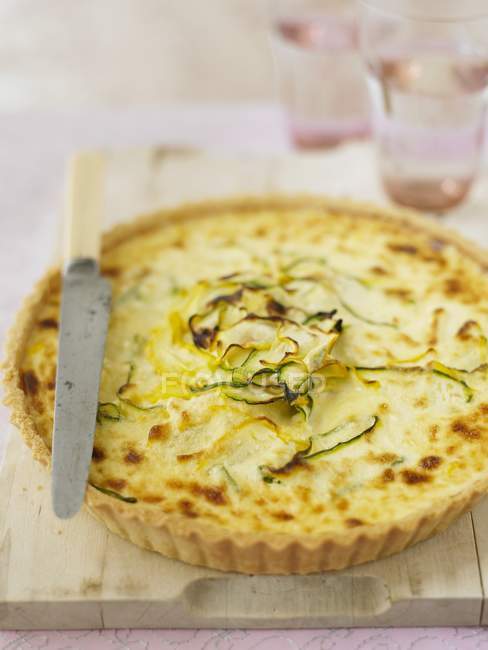 Courgette tart on wooden desk with knife — Stock Photo