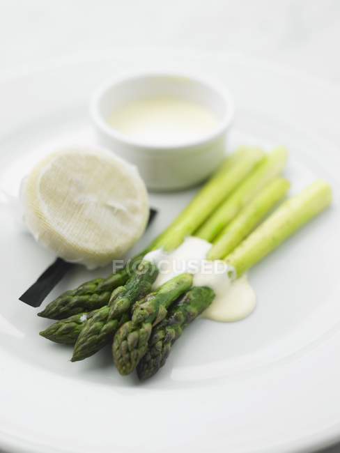 Зеленая спаржа с голландским соусом на белой тарелке — стоковое фото