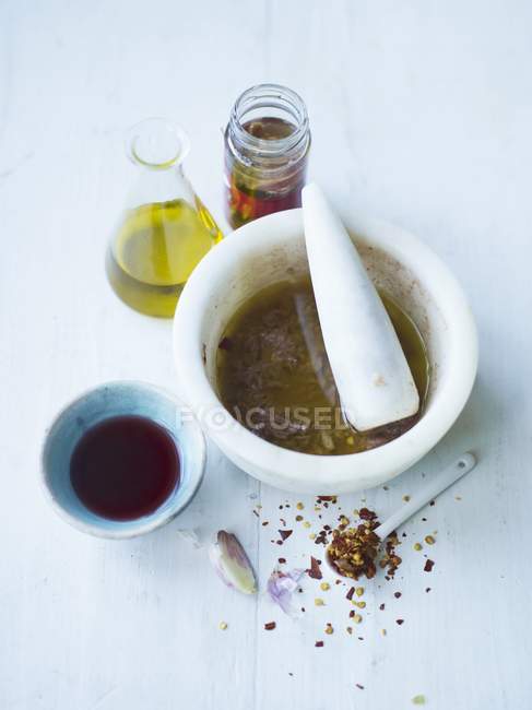 Condimento per insalata con peperoncino, acciughe, aglio e olio d'oliva su superficie bianca — Foto stock