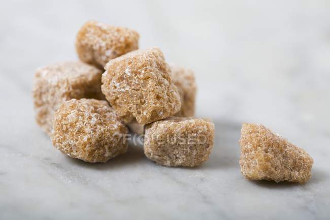 Nahaufnahme brauner Zuckerwürfel auf einer Marmoroberfläche — Stockfoto